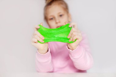 Cute girl playing with green slime. The girl holds in her hands and stretches the mucus . Slime toy, anti-stress toy clipart