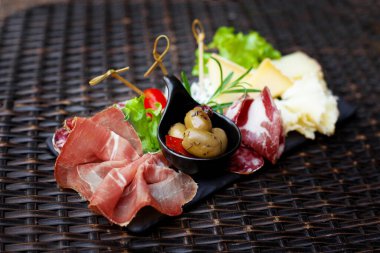 Dilimlenmiş et ve peynir aperatifi zeytin turşusu ve marul yapraklarıyla. Soğuk mezeler, gurme öğle yemeği. Yan görünüm