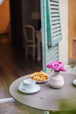 Bir buket pembe gül, kruvasan ve kahve. Balkonda Fransız Kahvaltısı