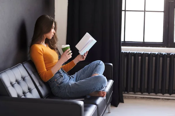 소녀는 집에서 소파에 커피를 공책을 읽습니다 에서의 — 스톡 사진