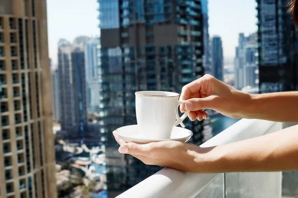 소녀는 현대식 건물의 배경에 발코니에서 커피를 마시는 — 스톡 사진