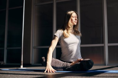 Açık renk saçlı çekici bir kadın yoga yapıyor. Yoga, fitness, sağlıklı yaşam tarzı