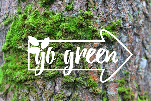 Inspirational banner Go Green banner decorated hand drawn leave, index on the green moss tree bark background. Quote for Earth day, ecological sign, protect nature label. Photo for care our planet