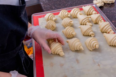 Mutfakta bir pasta şefi hamur işleri yapıyor. Şef, kruvasanı pişirmeden önce bir yemek tepsisinin üzerine serer. Mutfakta master dersi var. Yemek pişirme süreci. Adım adım. Öğretici