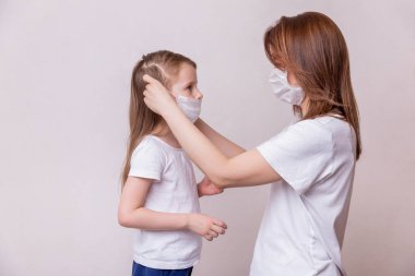 Koronavirüs karantinası kavramı. Annem kızına virüslere karşı koruyucu bir maske takıyor. Sağlık ve Tıp Teması.