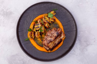 Hafif arka planda haşlanmış biftek, kızarmış patates ve kabak kreması. Avrupa mutfağı. Profesyonel bir şefin işi. Restoran menüsünden bir tabak. Üst görünüm.