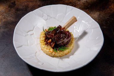 Bulgur ve balzamik soslu kuzu eti. Kemikte kuzu eti, bulgur, balzamik krem, roka ve kabak. Avrupa mutfağı. Profesyonel bir şefin işi. Restoran menüsünden bir tabak. Yan görünüm.