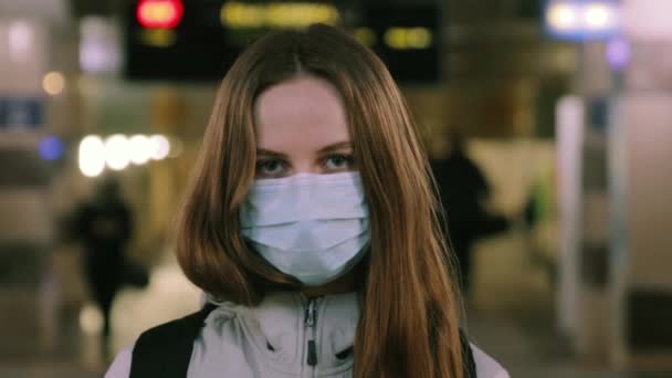 Joven chica caucásica se para en la estación de tren con máscara protectora en la cara — Vídeos de Stock