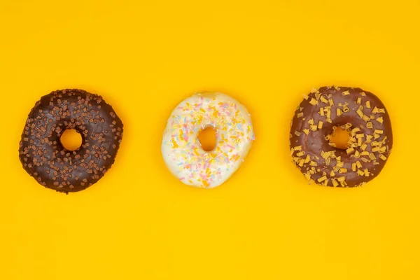 Zoete donuts op gele achtergrond. Dessert voedsel — Stockfoto