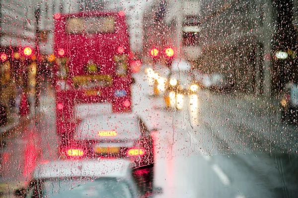 Regen in London Blick auf roten Bus durch regengesprenkeltes Fenster — Stockfoto