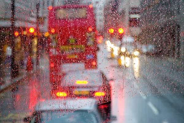 Pioggia a Londra vista su autobus rosso attraverso la finestra punteggiata di pioggia — Foto Stock