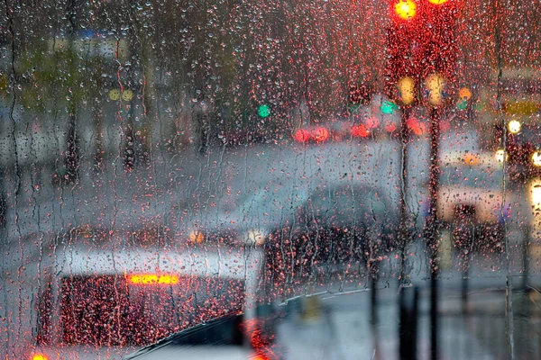 Pioggia a Londra vista su autobus rosso attraverso la finestra punteggiata di pioggia — Foto Stock