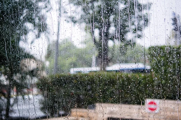 Scena di strada offuscata attraverso i finestrini dell'auto con goccia di pioggia — Foto Stock