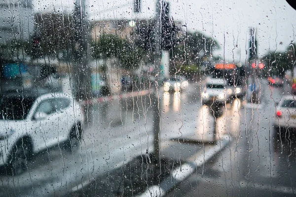 Unscharfe Straßenszene durch Autoscheiben mit Regentropfen — Stockfoto