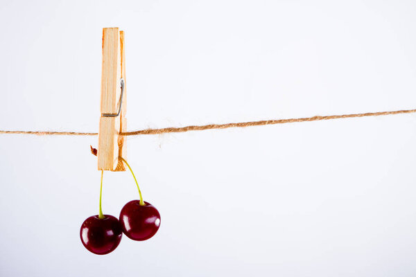 Cherry and rope on white background with clamp