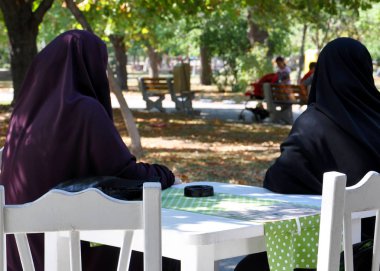parkta bir kafede bir masada oturan bir paranjas iki Müslüman kadın