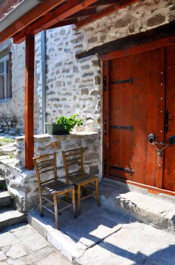 Bir ev ahşap kapının yanında bir gölgelik altında duran iki eski sandalye. Bir sokak bir dağ köyü