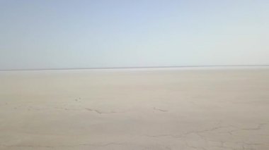 Maranjob Çölü 'nün panoramik manzarası. Drone yavaş yavaş kurumuş tuz gölü Namak 'a yaklaşıyor. Görünür tuz, kuru çatlaklar ve açık mavi gökyüzü.