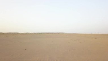 Maranjob Çölü 'nün yukarısından panoramik bir manzara. Bir İHA kumların ve kumulların üzerinden uçuyor. Görünür kum ve açık mavi gökyüzü