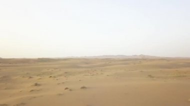 Maranjob Çölü 'nün yukarısından panoramik güzel manzara. Bir İHA kumların ve kumulların üzerinden uçuyor. Görünür kum, çimen, çalılar.