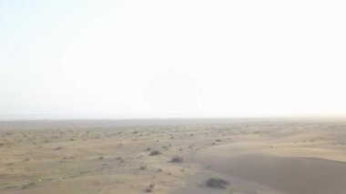 Maranjob Çölü 'nün panoramik güzel manzarası. Bir İHA kumların ve kumulların üzerinden uçuyor. Görünür kum, çimen, çalılar ve mavi gökyüzü.