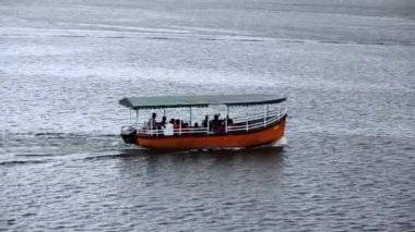 Gölde yüzen insanlarla dolu çatısı olan bir gezi teknesi. Diğer tekneler de görünür. Udaipur 'daki Pichola Gölü, Rajasthan, Hindistan.