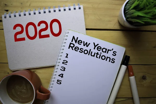 Resoluciones de Año Nuevo 2020 escriben sobre el libro con fondo de tabla de madera — Foto de Stock