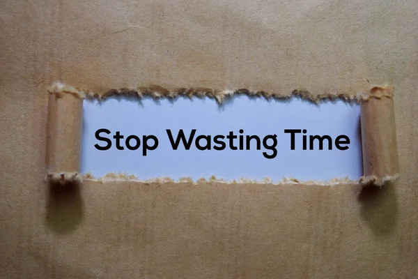 Stop Wasting Time Text written in torn paper