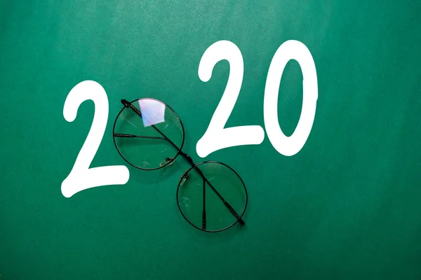 Счастливого Нового Года 2020 со стеклами, изолированными на цветном столе — стоковое фото