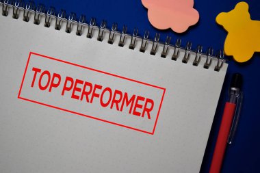 En iyi performans sanatçısı mavi arkaplanda izole edilmiş bir kitap üzerine yazar.