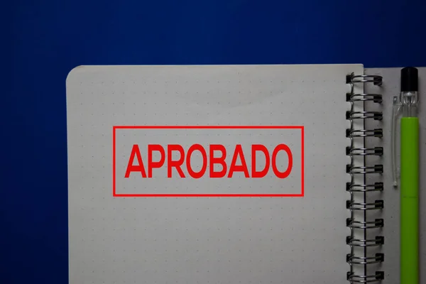 Aprobado scrivere su un libro lingua spagnola isolata su sfondo blu . — Foto Stock