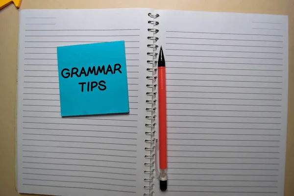 Grammatiktipps schreiben auf einen klebrigen Zettel, der isoliert auf dem Schreibtisch liegt. — Stockfoto