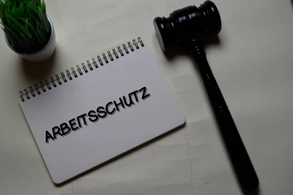 Arbeitsschutz пише на книзі з гавелем, ізольованим на Office Desk. Німецька мова це означає безпека праці — стокове фото