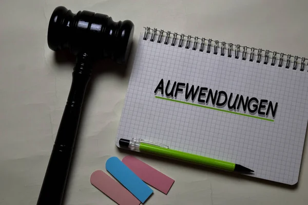 Ауфвендунген пише на книзі з гавелем, ізольованим на Office Desk. Німецька мова означає операційні витрати — стокове фото