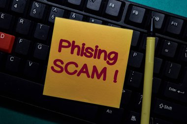Phising Scam! write on a sticky note isolated on Office Desk clipart