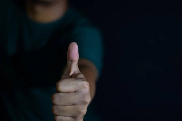 年轻男子的手势会竖起大拇指 或对深色的黑色背景给予认可 有选择地专注于手指 — 图库照片