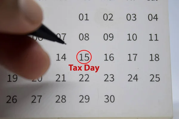 Tax Day on monthly Calendar and marked 15th isolated on office desk