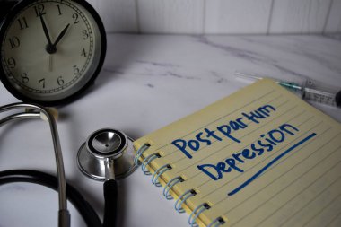 Postpartum Depresyonu Ofis Masası 'nda izole edilmiş bir kitap ve anahtar kelime üzerine yazıldı. Sağlık / Tıbbi Konsept