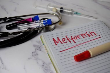 Metformin, Ofis Masası 'na izole edilmiş bir kitap ve anahtar kelime yazıyor. Sağlık / Tıbbi Konsept