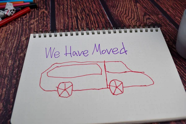 We Have Moved write on a book and drawing car Isolated on wooden table background