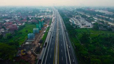 BEKASI, WESTJAVA, INDONESIA: MAYIS 12020: Yağmurdan sonra hareket eden arabalarla otoyolun çok katlı kavşak yolunun hava aracı görüntüsü. Arabalar bir yol kavşağında hareket ediyor.