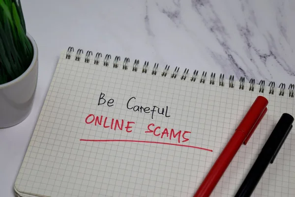 Be Careful Online Scams write on a book isolated on office desk