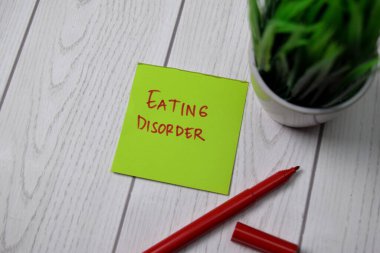 Ahşap masaya izole edilmiş yapışkan nota yeme düzensizliği yazılıyor.