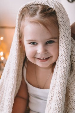 Sevimli küçük gülümseyen kız kaplı büyük kareli veya evde eşarp