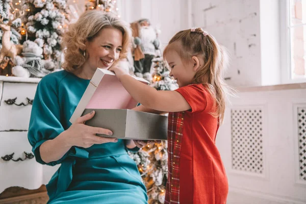 Presente de Natal surpresa - pequena menina e mulher na frente da árvore decorada — Fotografia de Stock