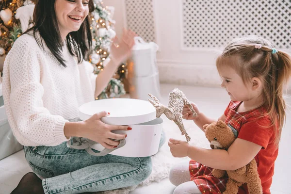 Presente de Natal surpresa - pequena menina e mulher na frente da árvore decorada — Fotografia de Stock