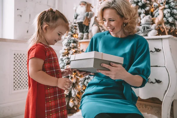 Presente de Natal surpresa - pequena menina e mulher na frente da árvore decorada Fotos De Bancos De Imagens