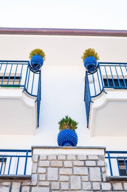 Traditional white and blue facades of the buildings decorated with plants in vibrant pots on the balconies in Vico Equensea a coastal town in Italy clipart