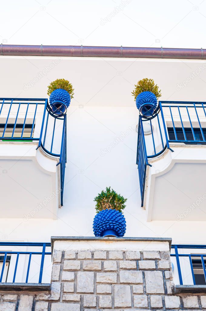 Traditional white and blue facades of the buildings decorated with plants in vibrant pots on the balconies in Vico Equensea a coastal town in Italy