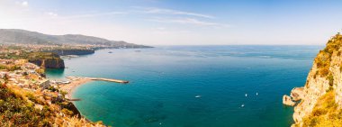 Yüksek uçurum manzarası, saf gök mavisi suyu, yüzen tekne ve gemileri, çakıl taşı plajları, Meta, Sant 'Agnello ve Napoli bölgesi yakınlarındaki Sorrento şehirlerinin kayalık çevresi.